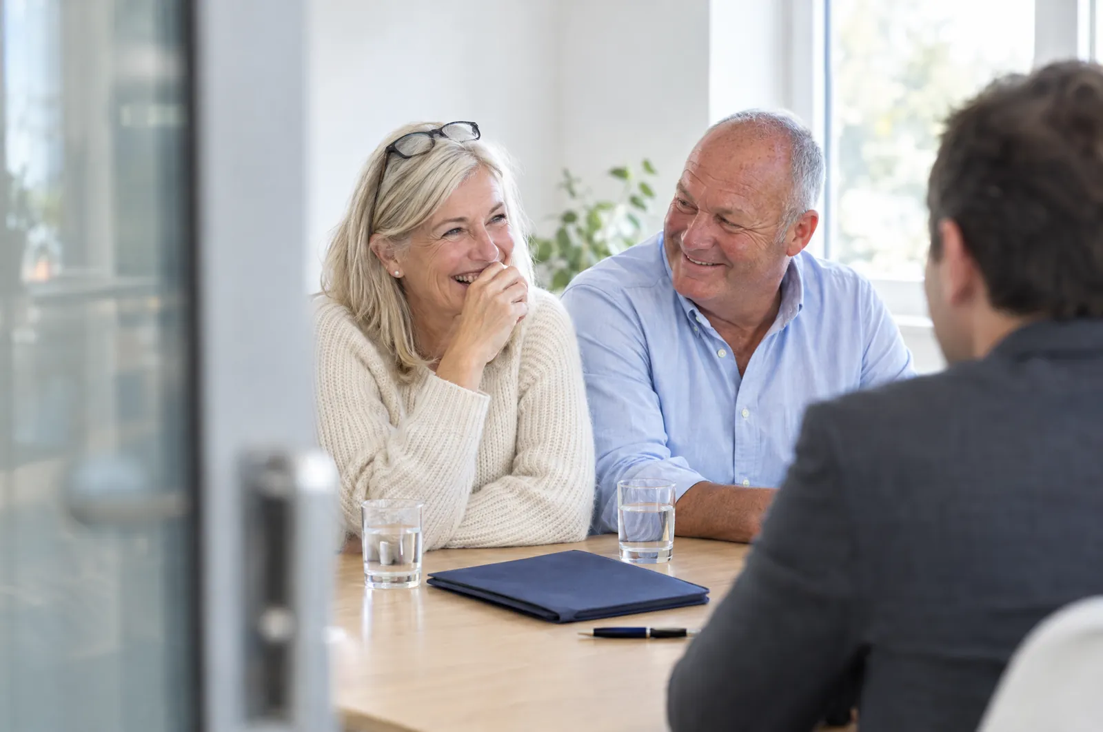A couple who own a family business laughing during a meeting with an advisor