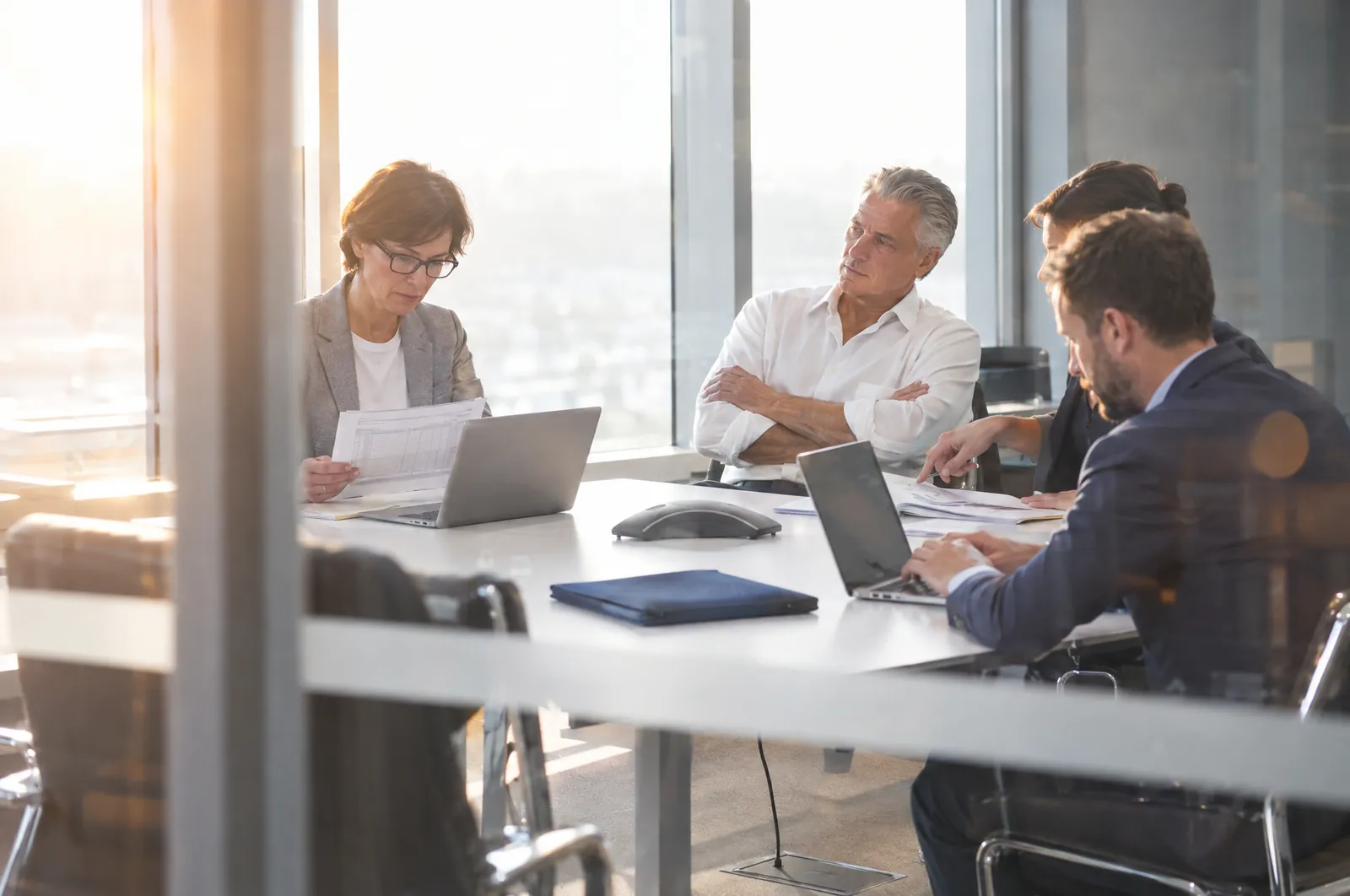 The leadership team of an established company in a meeting, seen through a glass wall
